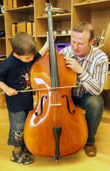 Lehrer unterrichtet einen kleinen Jungen am Cello