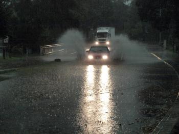 PKW und LKW befahren eine vom Starkregen überflutete Straße